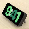 A black power bank with a screen displaying the time 9:41, propped up on a wooden surface. Voir les images du produit