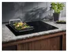 A modern kitchen countertop with an induction cooktop featuring a grill pan with food. Podgląd zdjęcia produktu