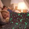Two children sleeping under a glowing blanket in a dimly lit room. Produktbild-Vorschau
