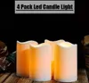 Four LED candles are arranged on a wooden surface with some decorative flowers to the left. Náhled obrázku produktu