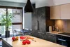 A modern kitchen island with fruits and vegetables on the countertop, with cabinetry and a dining area in the background. Produktbild-Vorschau