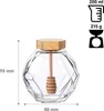 A clear product shot of a glass honey jar with a wooden lid and honey dipper, with dimensions and capacity indicated by text and icons. Náhled obrázku produktu