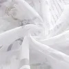 A close-up view of white sheer fabric with a floral pattern and text printed on it. Produktbild-Vorschau
