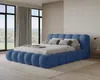 A bedroom with a large blue upholstered bed and large windows overlooking a landscape. Voir les images du produit