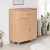 A wooden sideboard with a drawer and two doors, placed in a room with plants and a window in the background. Náhľad obrázku produktu