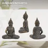 Three views of a Buddha statue in a meditative pose, presented against a neutral background with subtle floral elements. Náhľad obrázku produktu