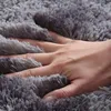 A hand is pressing into a soft, shaggy gray rug. Náhled obrázku produktu