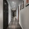 A modern hallway with dark doors and tiled floor, illuminated by ceiling lights. Produktbild-Vorschau