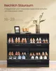 A black shoe cabinet filled with shoes, with decorative items on top. Produktbild-Vorschau