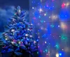 A frosted Christmas tree decorated with colorful LED lights, standing next to a wooden wall adorned with a string of lights. Produktbild-Vorschau