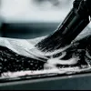 A close-up of a brush cleaning a textured surface with soap and water. Anteprima dell’immagine prodotto