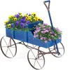A blue wooden wagon filled with yellow and purple pansies and pink asters, set against a white background. Produktbild-Vorschau