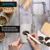 Hands labeling a glass storage container with a marker and sticker, surrounded by ingredients like chickpeas, dried herbs, and coffee beans. Náhled obrázku produktu