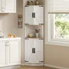 A white corner cabinet with wooden accents and black hardware, placed in a kitchen setting next to a window. Podgląd zdjęcia produktu