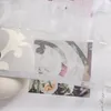A close-up view of a white sheer curtain with a cut-out pattern, layered over a floral image and a textured white object. Produktbild-Vorschau