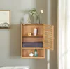A wooden wall cabinet with an open door, displaying shelves with toiletries and a folded towel. Produktbild-Vorschau