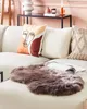 A faux fur rug is placed on a sectional sofa with decorative pillows. Produktbild-Vorschau