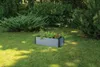 A raised garden bed filled with plants sits on a grassy lawn surrounded by bushes and trees. Náhľad obrázku produktu