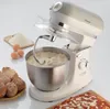 A vintage-style stand mixer is shown actively mixing dough, surrounded by ingredients and baked goods. Náhled obrázku produktu