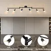 A modern black LED ceiling track light fixture with six adjustable spotlights, shown mounted on a ceiling above a living room setting. Three inset circular images demonstrate the rotational capabilities of the spotlights. Podgląd zdjęcia produktu