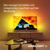 A television displaying a vibrant image of elephants and a tree at sunset, with ambient lighting illuminating the wall behind it. Produktbild-Vorschau