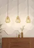 Three gold pendant lights hang above a wooden dresser with decorative vases. Náhled obrázku produktu