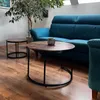 A living room scene with a teal couch and two round coffee tables. Produktbild-Vorschau