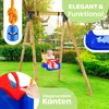 A baby is swinging on a colorful baby swing set in a grassy backyard. Produktbild-Vorschau