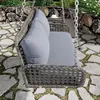 A hanging swing chair with cushions on a stone patio in a garden setting. Podgląd zdjęcia produktu