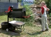A woman is using a rotary sieve machine to sift soil into a wheelbarrow in an outdoor setting. Náhľad obrázku produktu