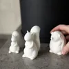 Three small white ceramic animal figurines (a hedgehog, a squirrel, and another animal) are placed on a gray surface in front of a dark pot. A hand is reaching in to touch the hedgehog figurine. Produktbild-Vorschau