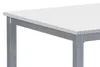 A close-up view of a modern dining table with a white top and gray metal legs. Náhled obrázku produktu