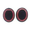 Two black circular ear pads with red adhesive tape on a white background. Náhled obrázku produktu