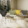 Four modern chairs in different colors are arranged in a living room setting. Produktbild-Vorschau