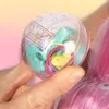A hand holding a clear plastic ball filled with small toys. Podgląd zdjęcia produktu