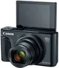 A black Canon PowerShot SX740 HS camera with its screen flipped up, shown against a white background. Produktbild-Vorschau