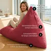 A woman is sitting on a large red beanbag chair in a bright, modern living room with large windows. Voir les images du produit