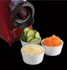 A red food processor attachment is shown with three bowls of prepared ingredients: sliced cucumbers, shredded cheese, and shredded carrots. Produktbild-Vorschau