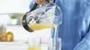 A person is pouring orange juice from a blender pitcher into two glasses. Anteprima dell’immagine prodotto