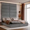 A bedroom scene with a bed and a large upholstered headboard. Produktbild-Vorschau