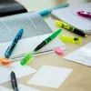 Highlighters and sticky notes are scattered on a desk next to an open book. Náhled obrázku produktu