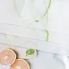 A close-up view of a white sheer curtain with green embroidered floral patterns, layered over a wooden cutting board with two grapefruit slices and a mint leaf. Produktbild-Vorschau