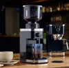 A coffee grinder and espresso machine are set up on a wooden counter in what appears to be a cafe. Náhled obrázku produktu