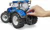 A hand is shown adjusting a detail on the back of a blue toy tractor. Voir les images du produit