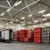 Interior of a warehouse with stacks of red and green crates, a trailer, and overhead lighting. Produktbild-Vorschau