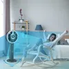A woman relaxing in a rocking chair in a bedroom, with a fan in the foreground. Produktbild-Vorschau