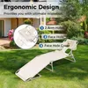 A beige foldable lounge chair with a headrest is set up on a green lawn in front of a house. Produktbild-Vorschau