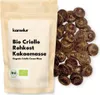A bag of organic cocoa mass next to a pile of cocoa nibs. Produktbild-Vorschau