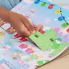 A person's hand is placing a pop-up Christmas tree onto an open advent calendar. Produktbild-Vorschau
