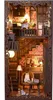 A miniature dollhouse-like structure, resembling a cozy room with bookshelves, stairs, and furniture, illuminated by warm lighting. Voir les images du produit